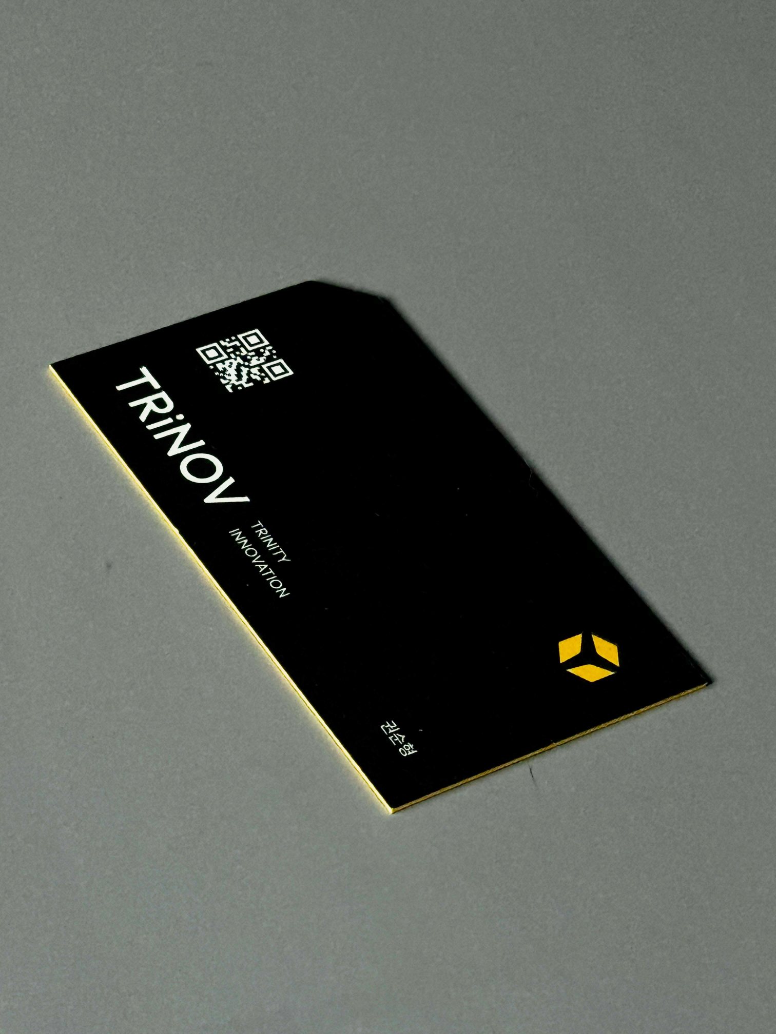 Business card printed with the TRiNOV wordmark, a QR code and a gold logo on black